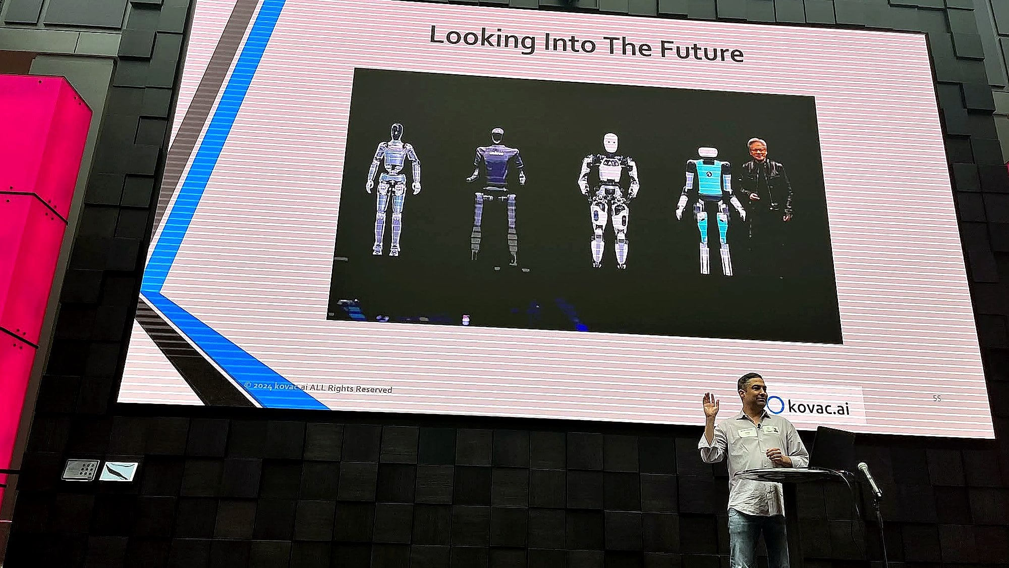 Chris Kovac delivering a keynote on stage with a large presentation screen behind him